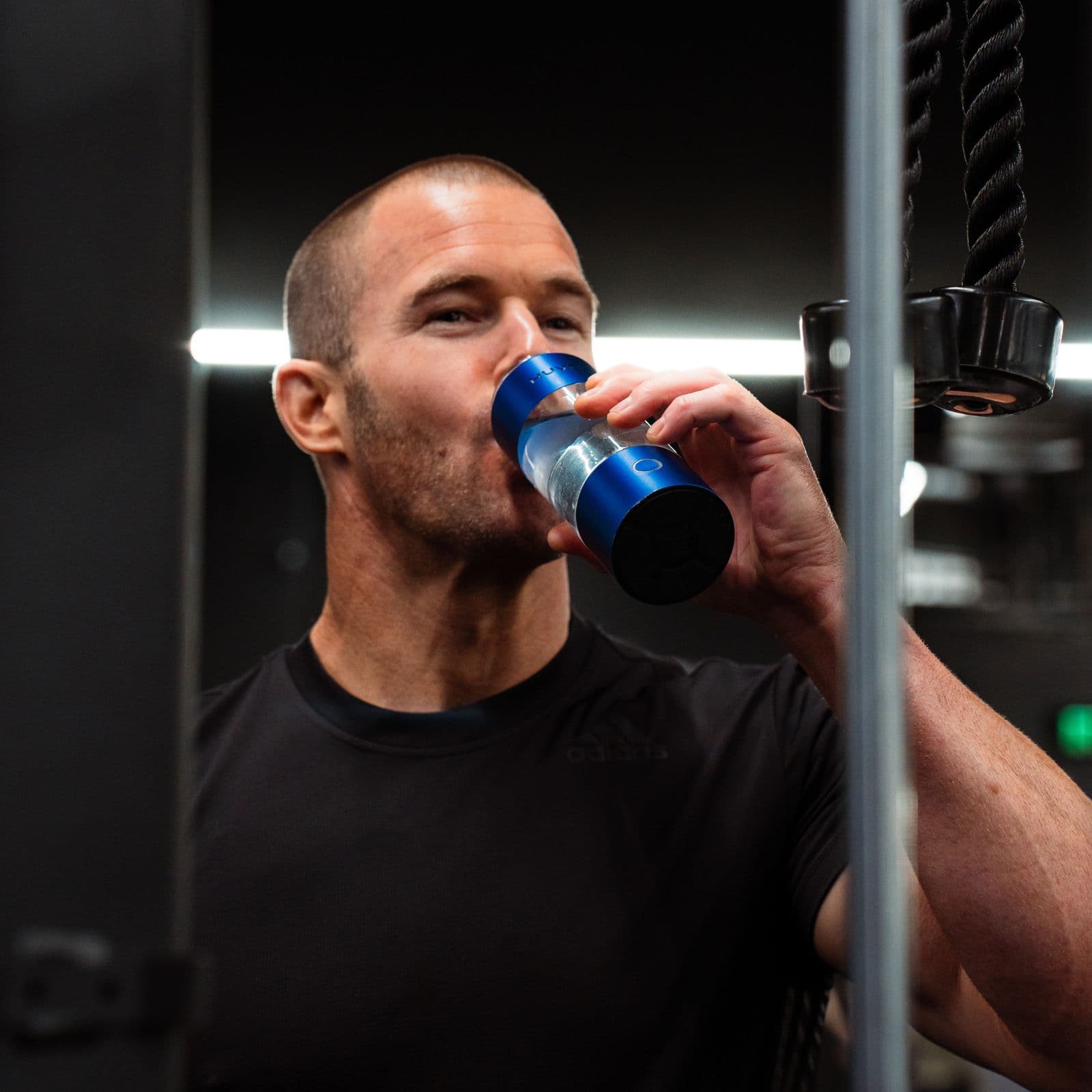 Man drinking from a HUVE Perform hydrogen water bottle in a gym
