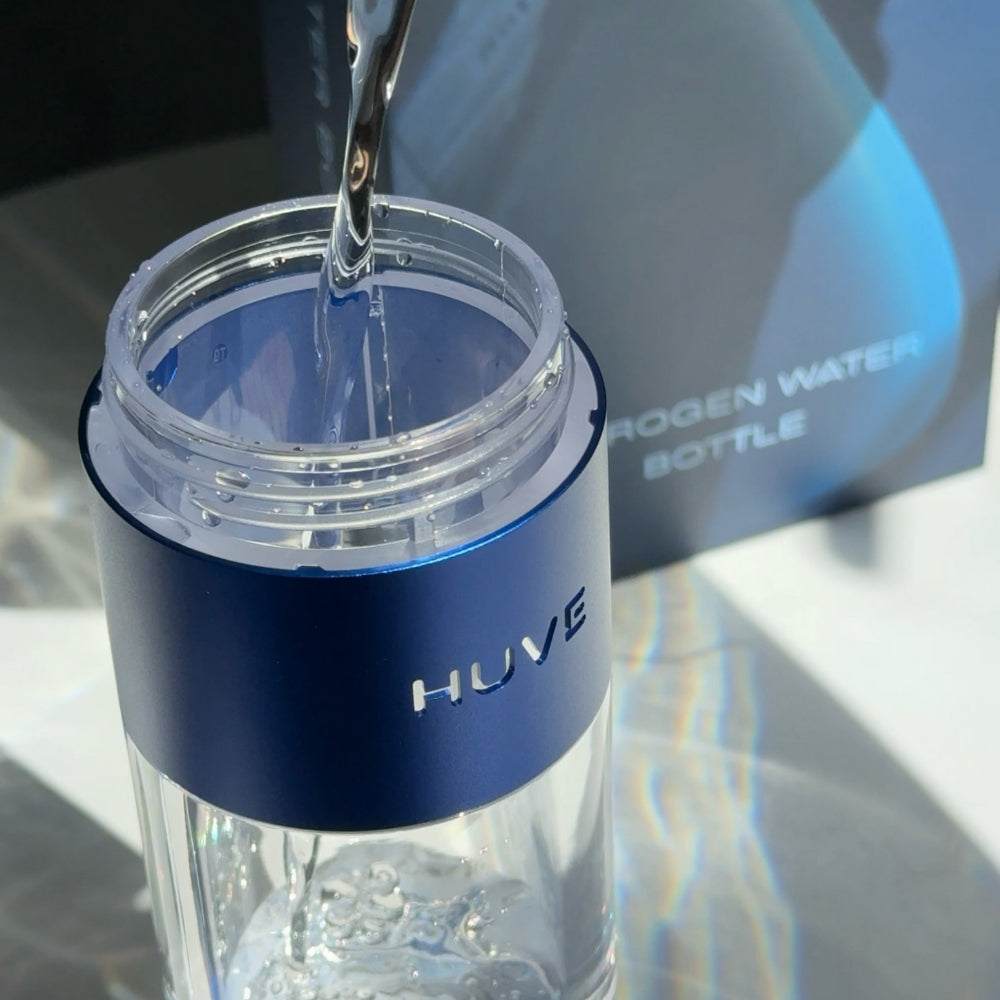HUVE Perform hydrogen water bottle in cobalt blue shown with the lid removed with water being poured into the bottle