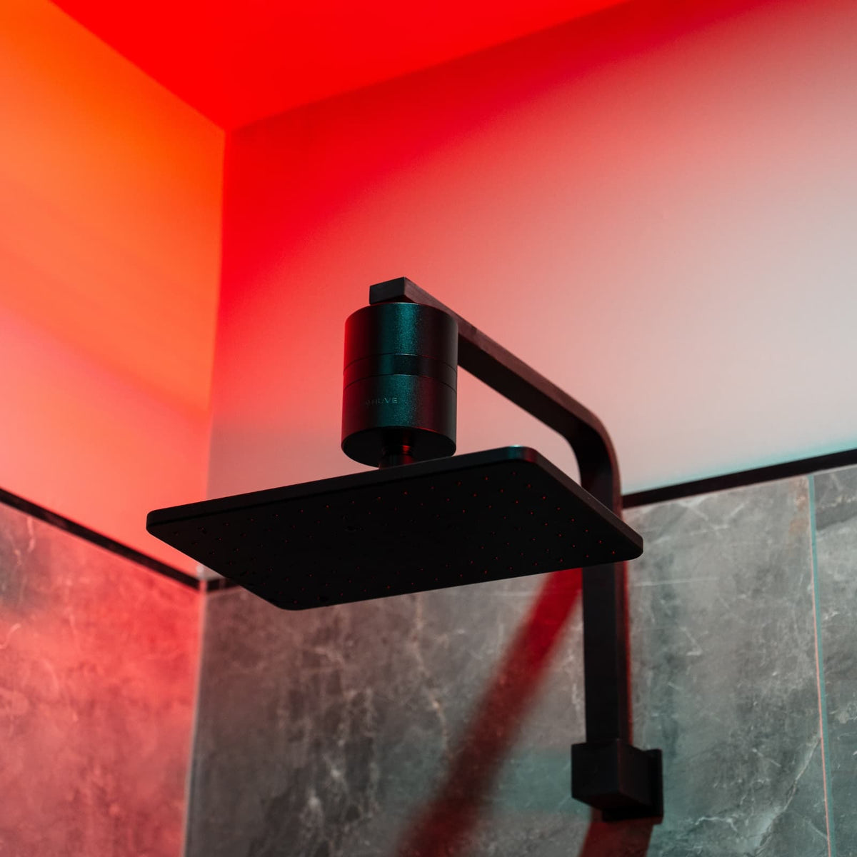 HUVE Flow shower filter on a black rain shower head under red lighting