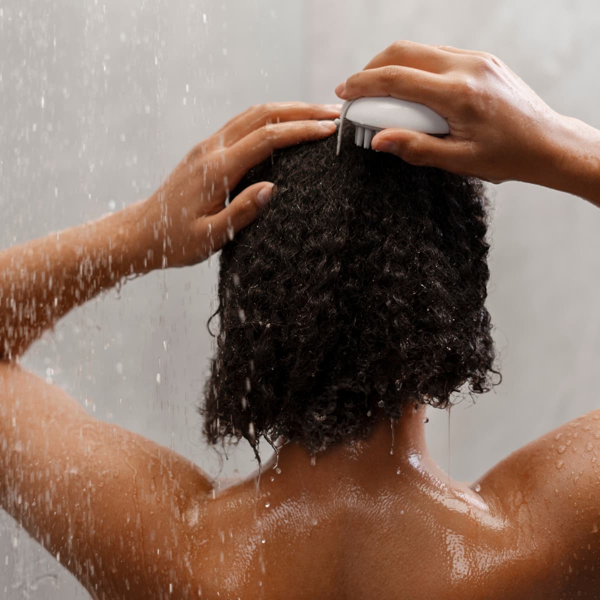 Person washing hair in the shower to illustrate everyday water exposure and hair care routine