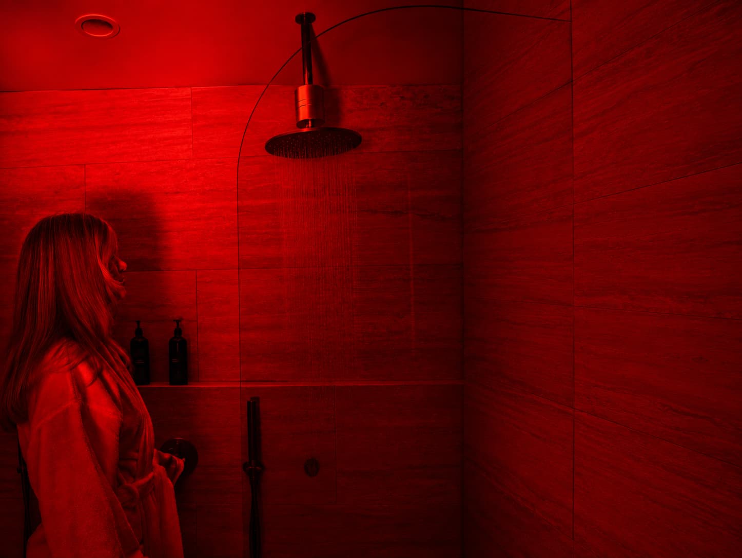 Woman in shower under HUVE Flow filtered water with red light therapy