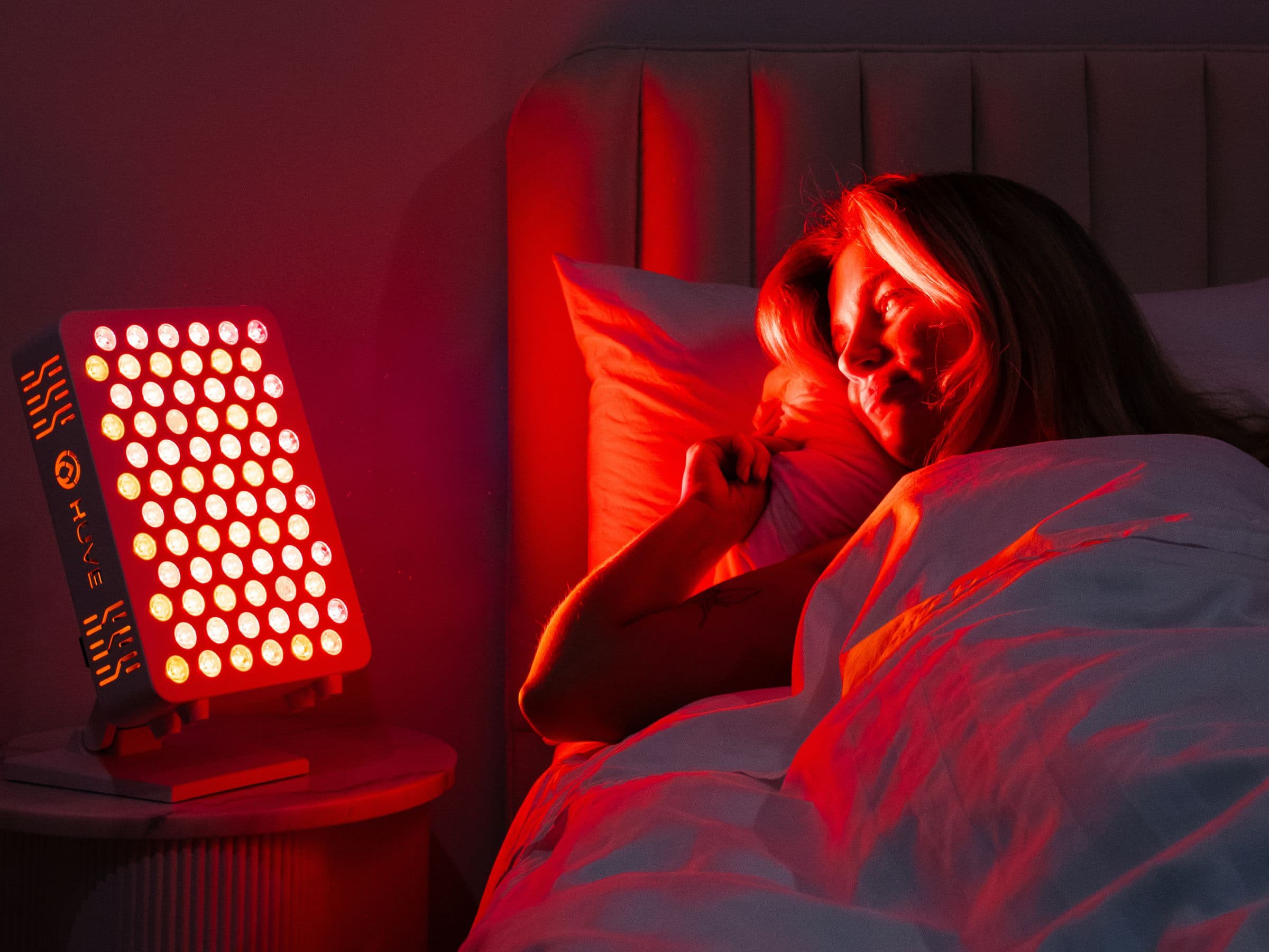 HUVE Luma red light therapy panel beside bed at night