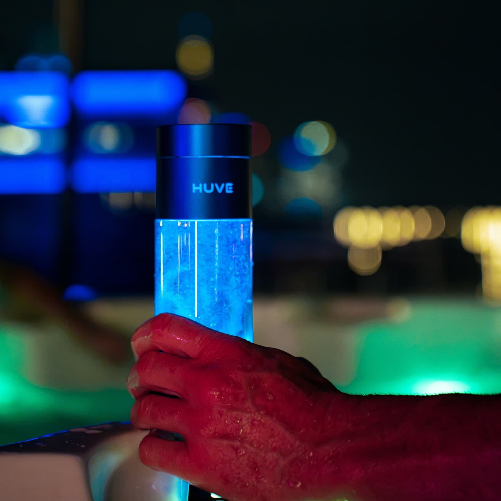 Hand holding a glowing HUVE Perform hydrogen water bottle at night