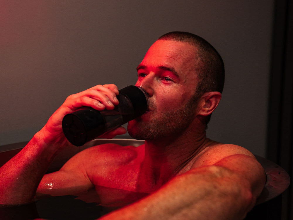 Man drinking from HUVE Perform bottle during ice bath